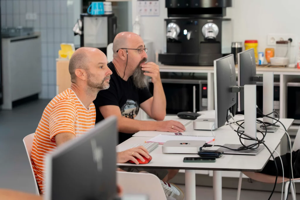 Dos empleados de WATA Factory atentos al escenario durante las explicaciones de Kubernetes.