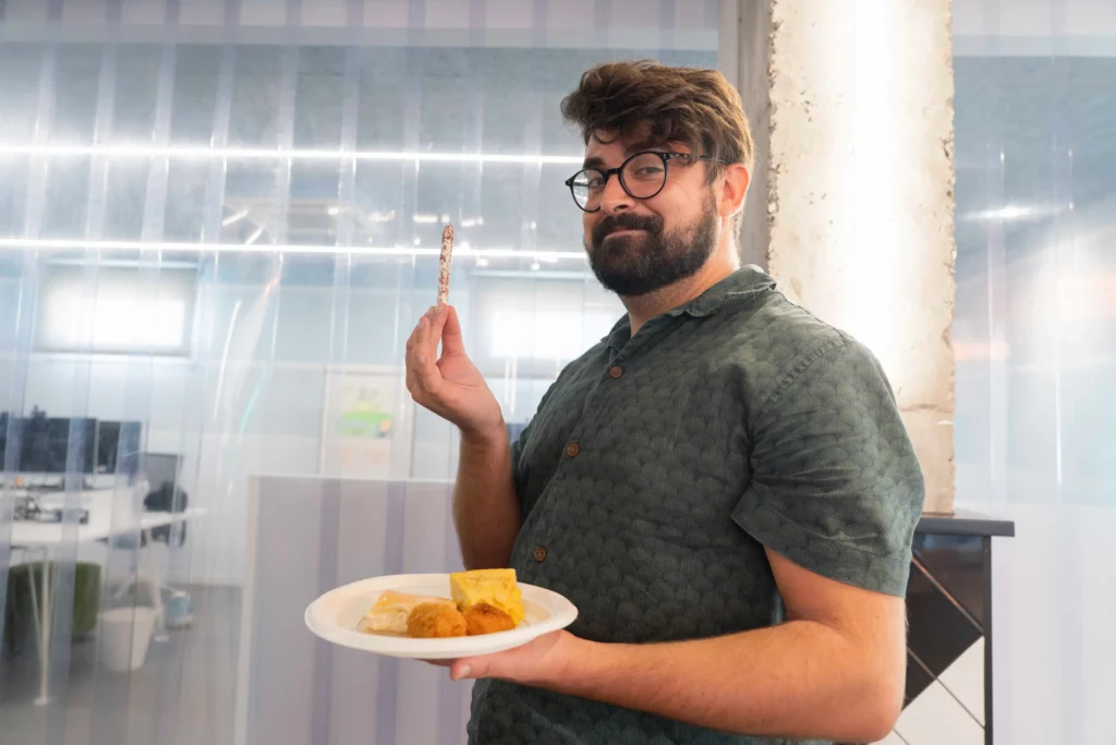 Mitarbeiter von WATA Factory zeigt stolz seinen Teller mit ausgewähltem Essen vom Mittagsbuffet.