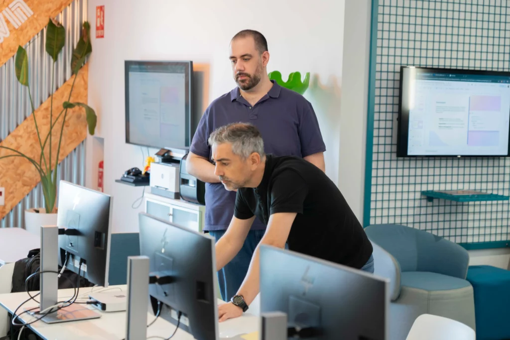 Dos empleados de WATA Factory observan con interés la pantalla durante el taller de DevOps y Kubernetes.