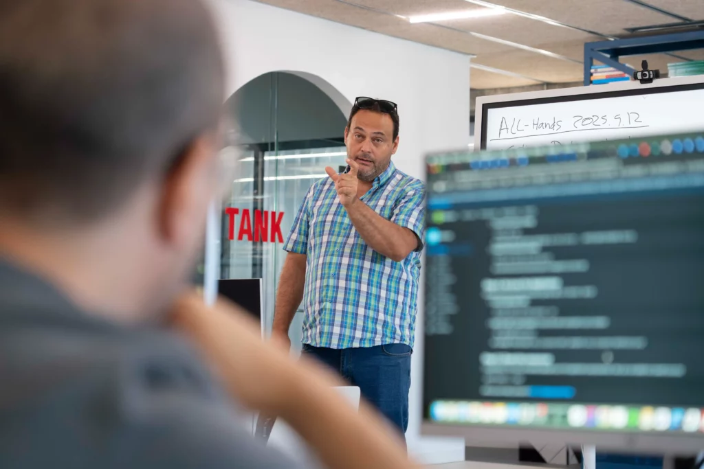 Vista desde el ordenador de un empleado hacia Pedro G., que resuelve dudas sobre DevOps y Kubernetes.