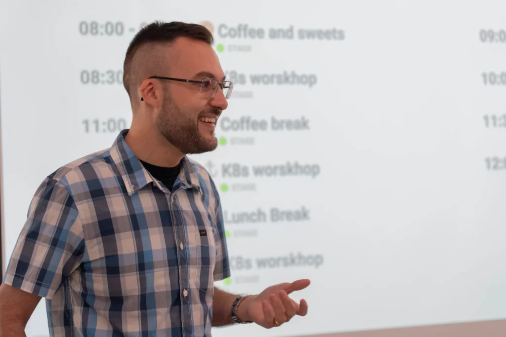 Eliezer L., Direktor von WATA Factory, lächelt, während er die Agenda des All Hands zu Kubernetes und DevOps präsentiert.