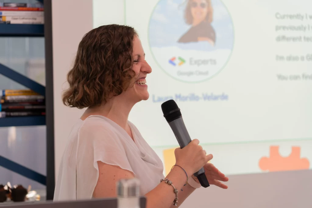 Laura Morillo-Velarde lächelt mit Mikrofon in der Hand während ihrer Präsentation über DevOps und Kubernetes bei WATA Factory.